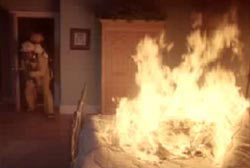 Firefighter entering a room that contains a bed engulfed in flames