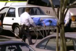 A police officer wheeling the covered body of Matt onto an ambulance