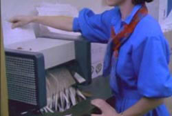 A woman puting Franke's papers through a paper shredder