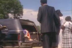 O'Neal Moore in a casket in the back of a hearse as his family grieves