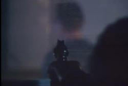 A man cast in shadow aiming a revolver at Ralph through a window