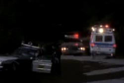 A police officer and ambulance arriving at the scene of a crashed police cruiser