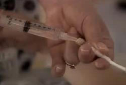 A person injecting a liquid into a tube through a syringe