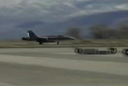 A jet plane touching down on the landing strip of a local air base