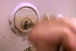 A hand shoving a key into a key hole