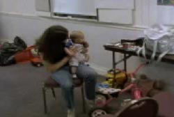 Patty holding a baby in her lap in what looks to be a classroom