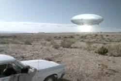 A car stopped in the desert facing a large disck shaped metallic craft in the sky