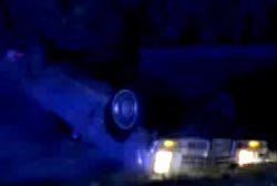 An overturned car in the middle of night with its headlights on