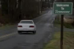 Blair driving a white car down a road with a sign tha reads 'Welcome to Tennessee