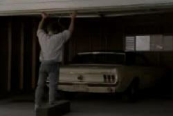 A man lifting a garage door open to find a car inside