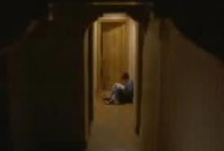 Chaim sitting against a wall reading a book in the hallway outside his room