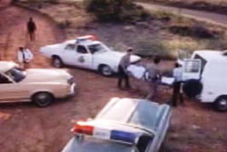 Police officers and paramedics wheeling away the covered body Chuck Morgan on a stretcher