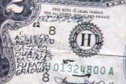A $2 bill with various alphabetic markings scribbled on it