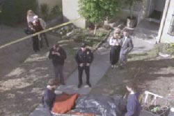 Police watching paramedics wheel the body of Crystal Spencer away on a stretcher outside of her apartment