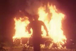 The shilouette of a man running from a burning car