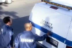 Two police officers at the back of a county coroner vehicle