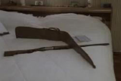 A rifle and gun sleve ontop of a white bed