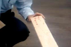 Investigator examining a bloodied 2x4