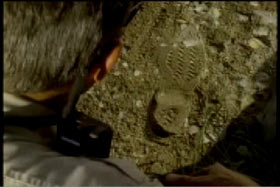 Police officer examining a boot print in the dirt