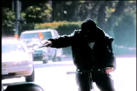 Lopez on a bycicle wearing a ski-mask aiming his gun at Carlos Hernandez