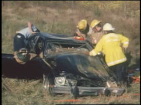 Fire fighters and investigator examine the wreckage of a fatal car crash