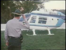 Police officer tipping his hat to a grounded helicopter