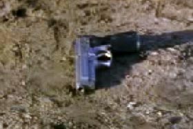 A silver pistol on a dirt floor