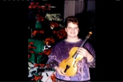 Margie Jelovcic in a purple sweater holding a violin