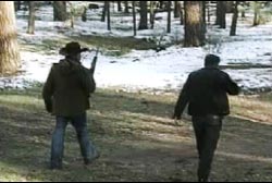Two police officers armed with rifles patroling a snowy forest