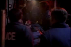 A police officer being carried into an ambulence by paramedics 
