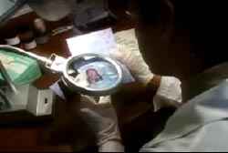 An investigator using a magnifying glass to examine a females forged passport