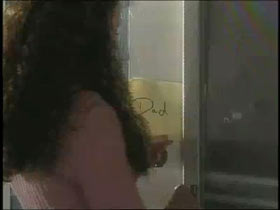 A girl slips a note with the words Dad written on it through a door