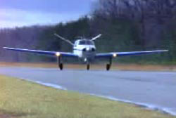 Small airplane touching down on a landing strip in the woods
