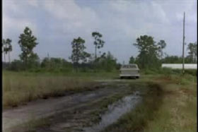 A pickup truck driving away from prison down a muddy road